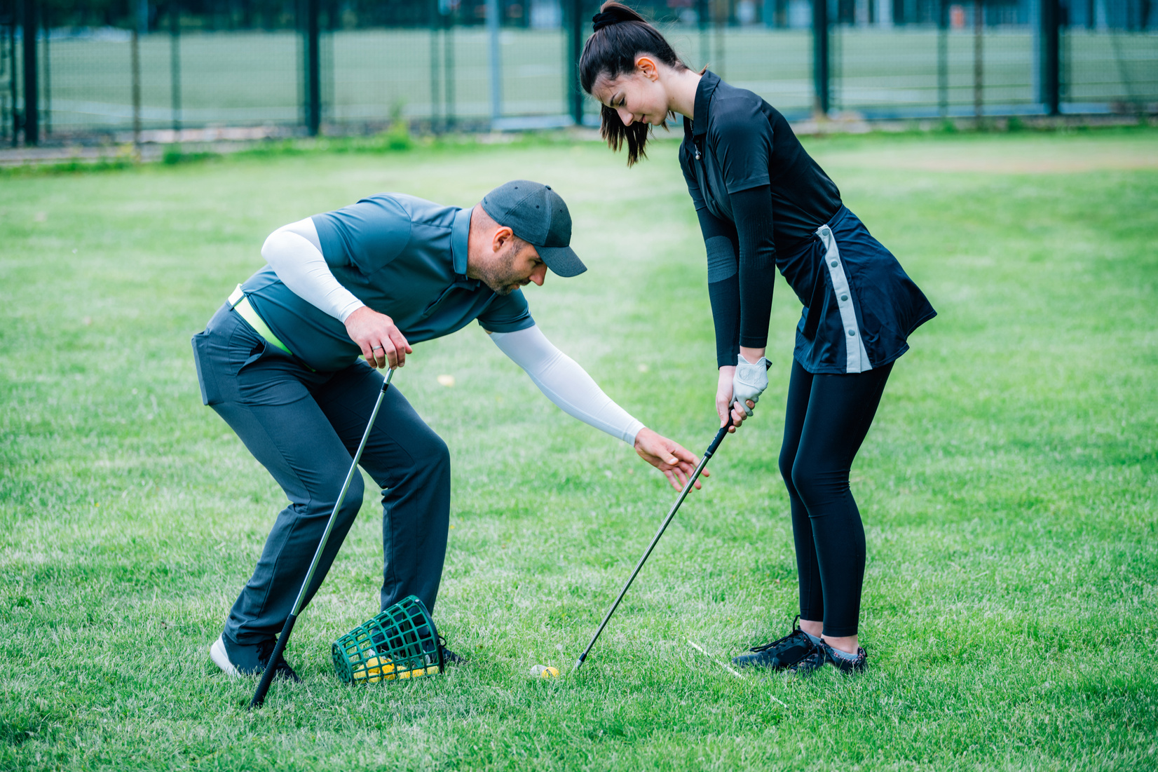 Individual golf lesson. Young woman having a golf lesson with golf instructor